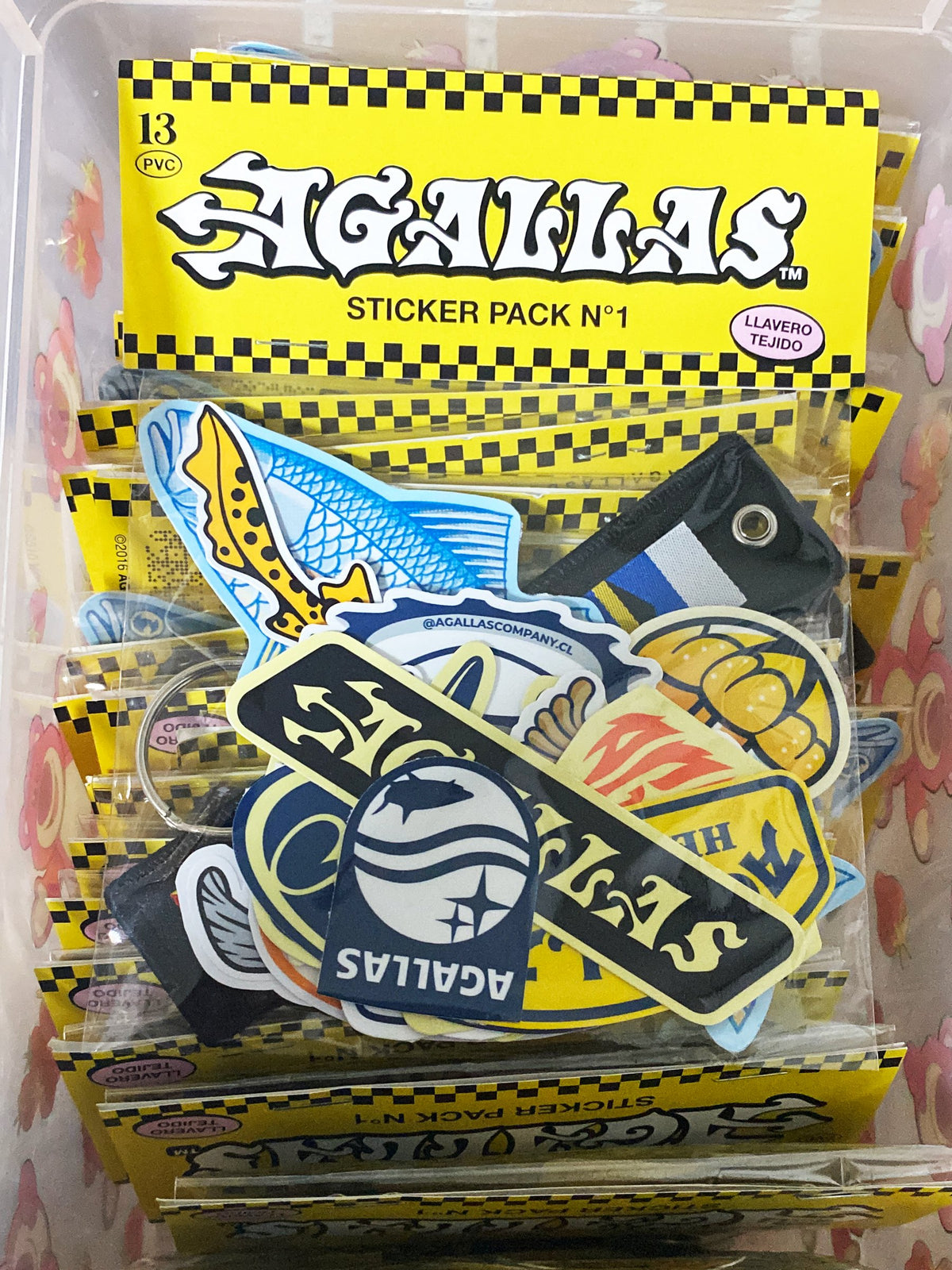 Sticker Pack N°1 de Agallas Co. en su empaque amarillo con llavero tejido de banderas náuticas